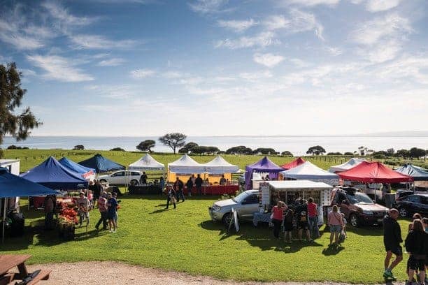 a green rural paddock with tents and people. A farmers market is one of the best things to do on Phillip Island