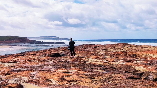 A lady looking at the beach while standing on some rocks at Forest Cave in Phillip Island