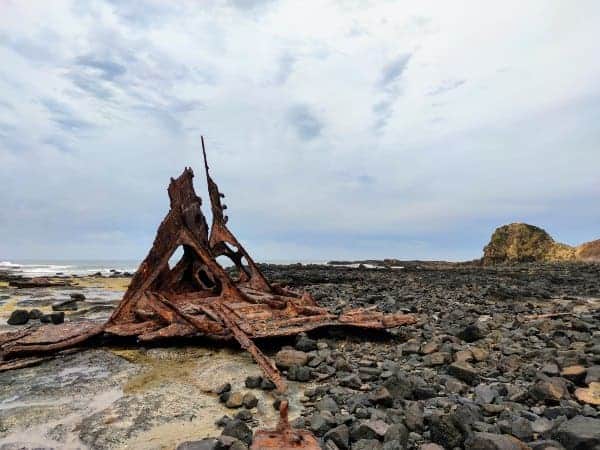 a rocky beach area with a decaying part of a shipwreck
