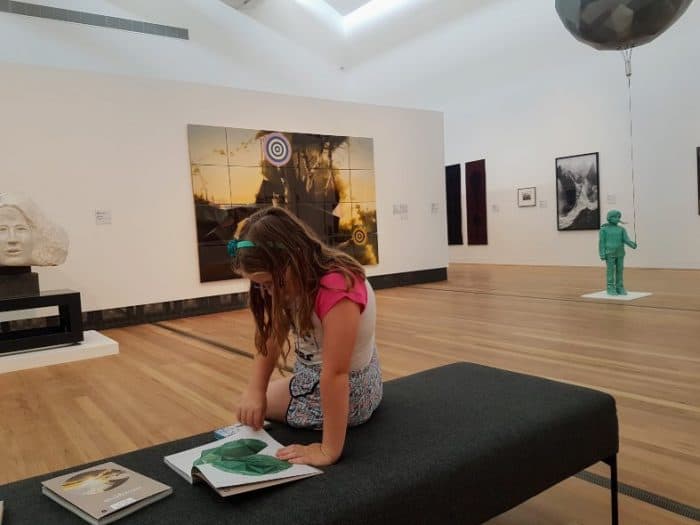 A young girl at the Gippsland art gallery in Sale looking at some books